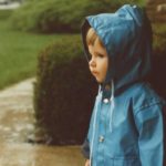 A one year old girl in a raincoat.