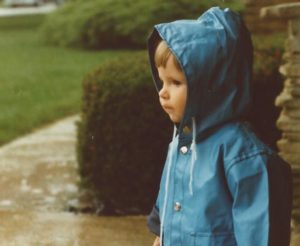 A one year old girl in a raincoat.